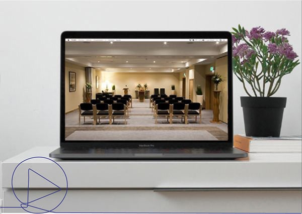 Funeral service stream on a laptop placed on a desk with flowers and books 