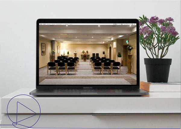 Funeral service stream on a laptop placed on a desk with flowers and books Funeral service stream on a laptop placed on a desk with flowers and books